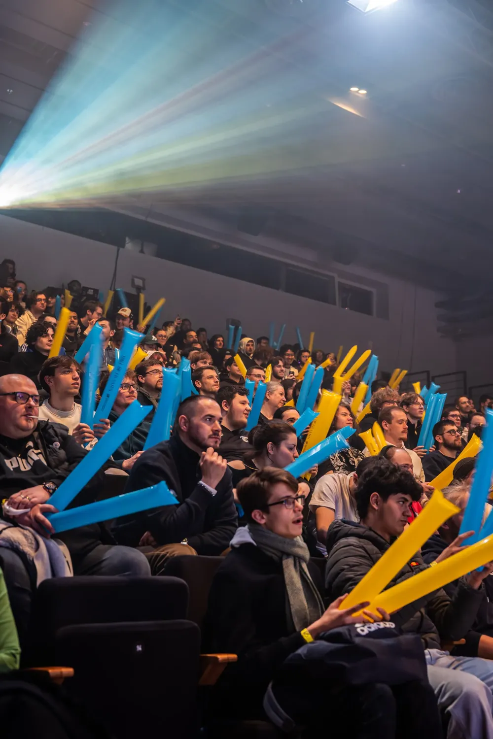 La salle comble sous les faisceaux lumineux, bâtons gonflables bleus et jaunes en main.