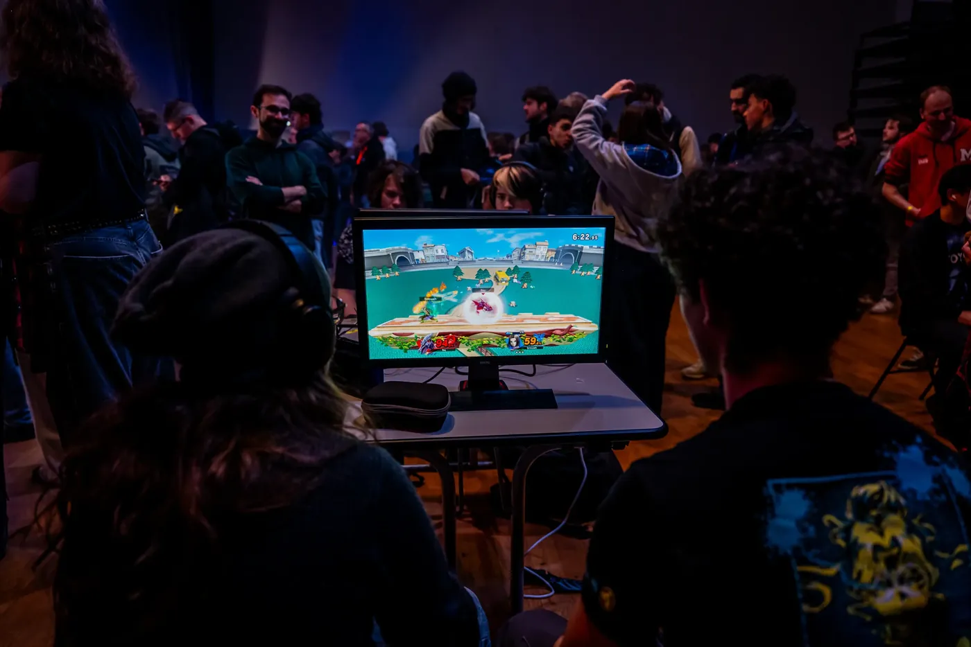 Un match de Super Smash Bros. sur un poste de jeu, au milieu des joueurs.