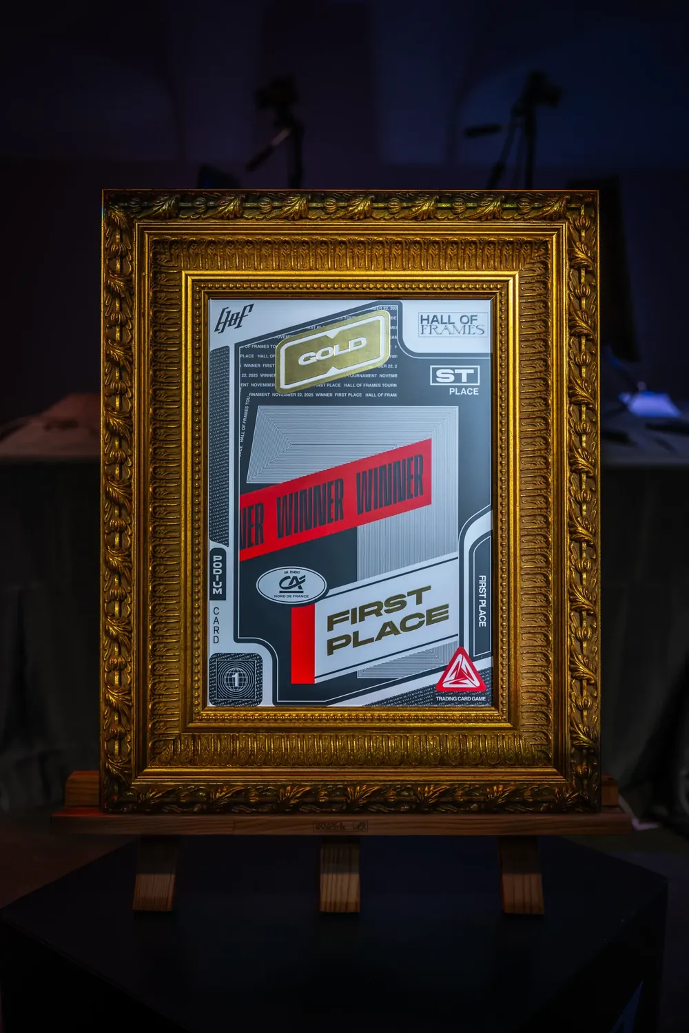 Le trophée, une carte Gold First Place dans un cadre doré posé sur un chevalet.