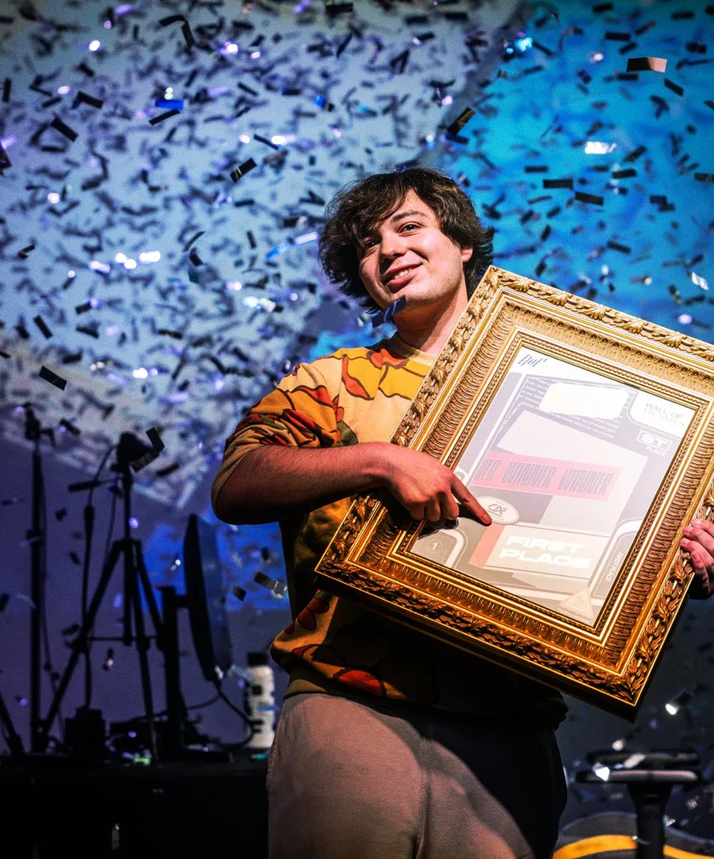 Le vainqueur brandit le trophée en cadre doré sous une pluie de confettis.