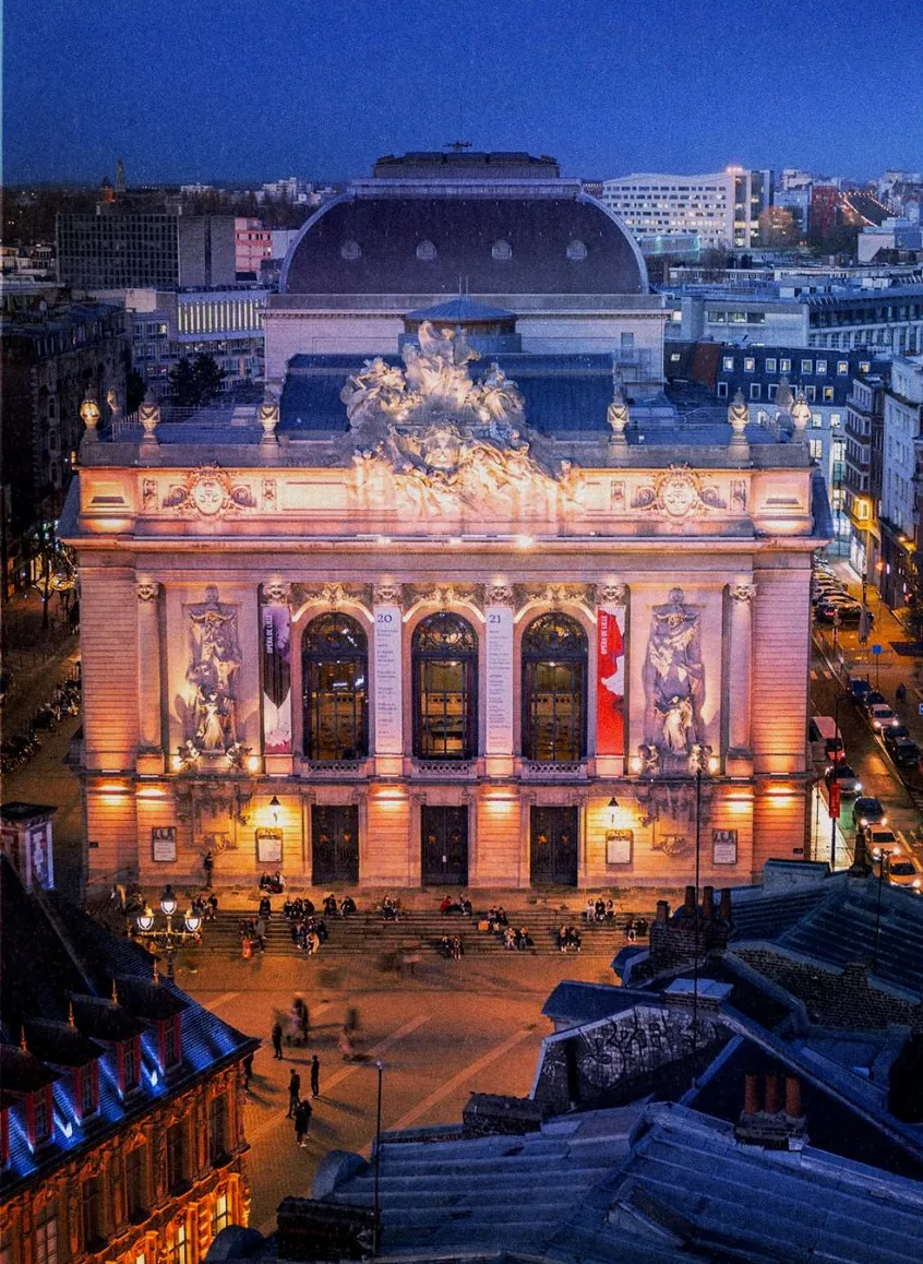 La façade illuminée de l'Opéra de Lille à la tombée de la nuit.