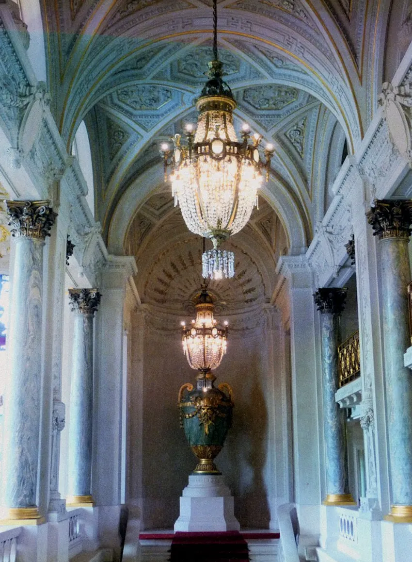 Une galerie à colonnes de marbre éclairée par des lustres de cristal.